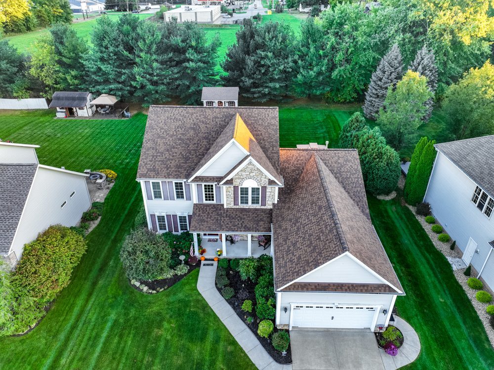 Aerial drone photo of a completed charcoal shingle roof on a two-story home with an attached garage in Northeast Ohio — Firestone Roofing & Restoration.