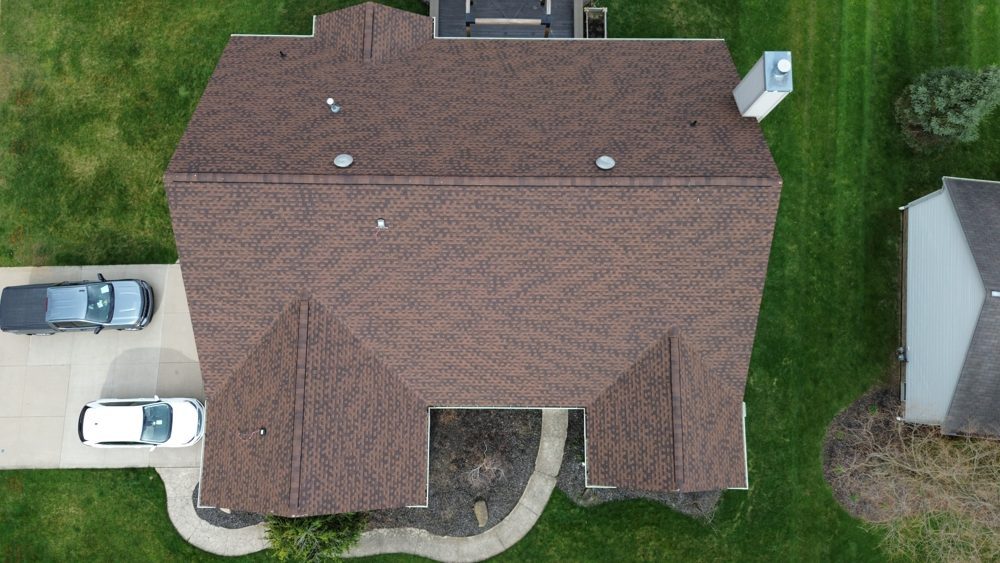 Aerial drone photo of a finished brown shingle roof and attached garage on a Northeast Ohio home by Firestone Roofing & Restoration.