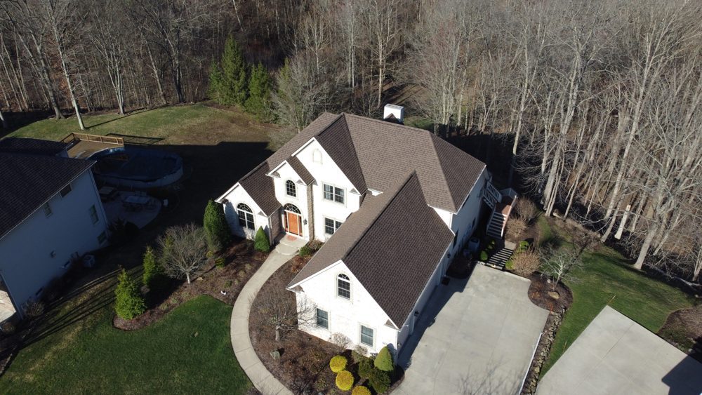 Top-down drone photo of a completed gray shingle roof on a Northeast Ohio home with a circular driveway, by Firestone Roofing & Restoration.