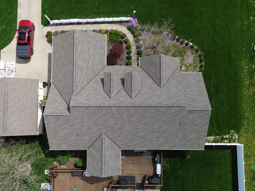 Aerial drone photo of a large completed light-gray shingle roof with multiple gables on a Northeast Ohio home by Firestone Roofing & Restoration.